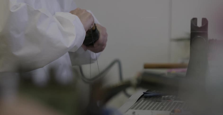 A person tying a string across a piece of wood in a lab