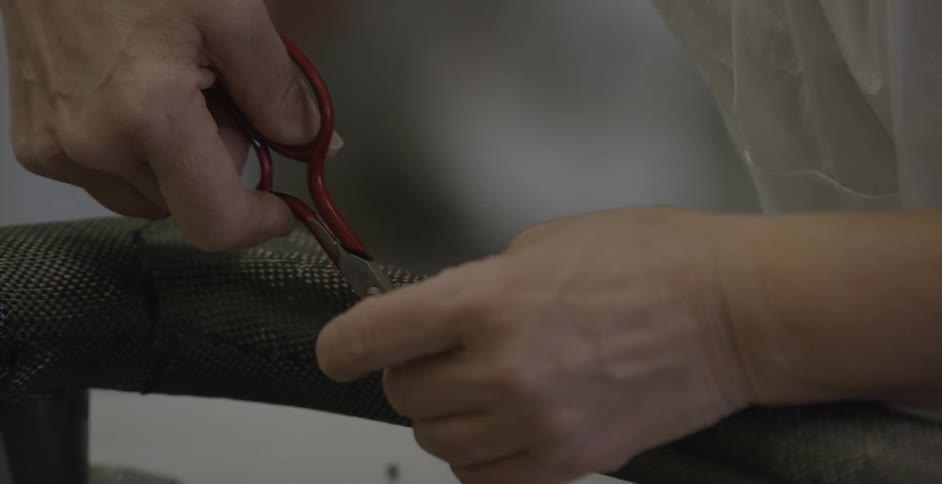 Person cutting fabric on a long object