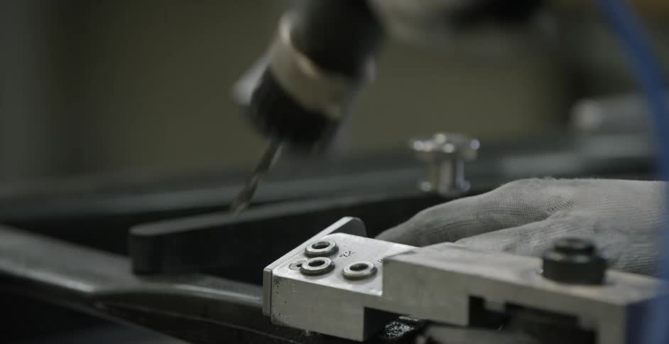 A factory worker uses a drill