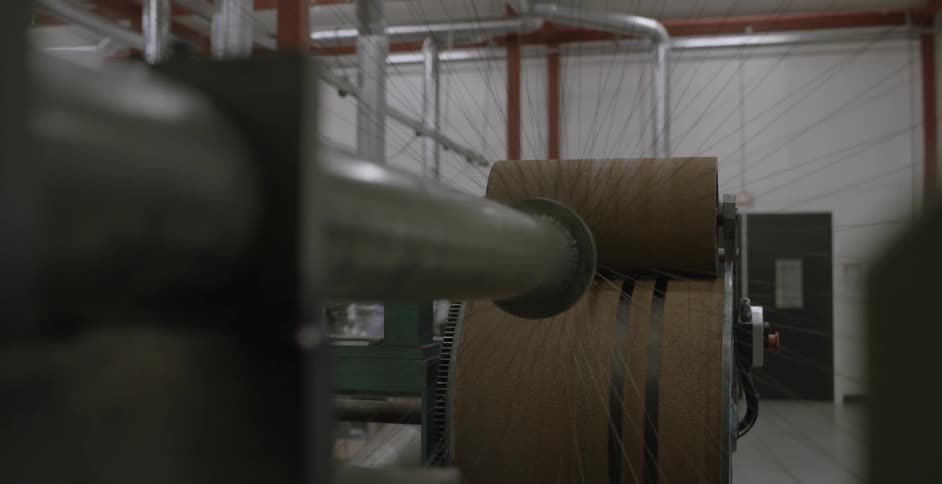 Many threads reach out from a spindle in a manufacturing plant