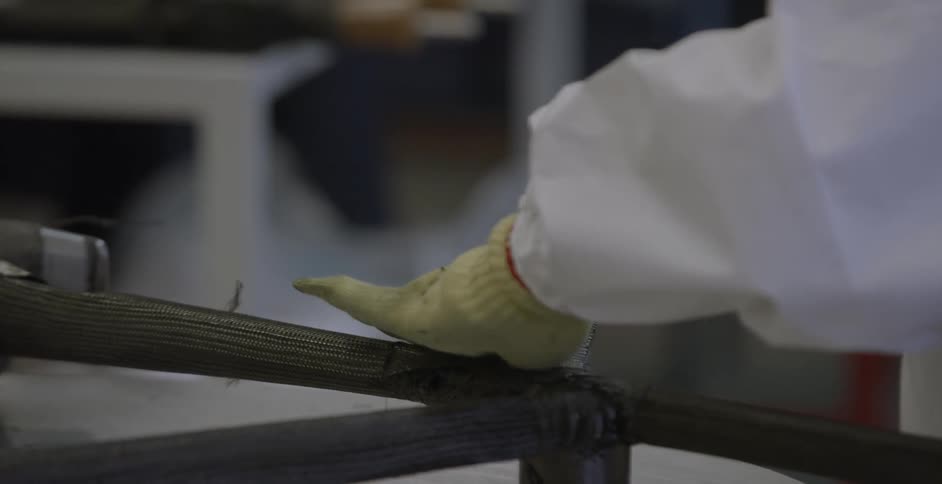A man holding a piece of equipment and working on something that is on a table and he is wearing gloves