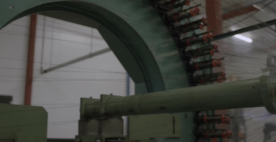Spindles are winding thread on an industrial machine during the day