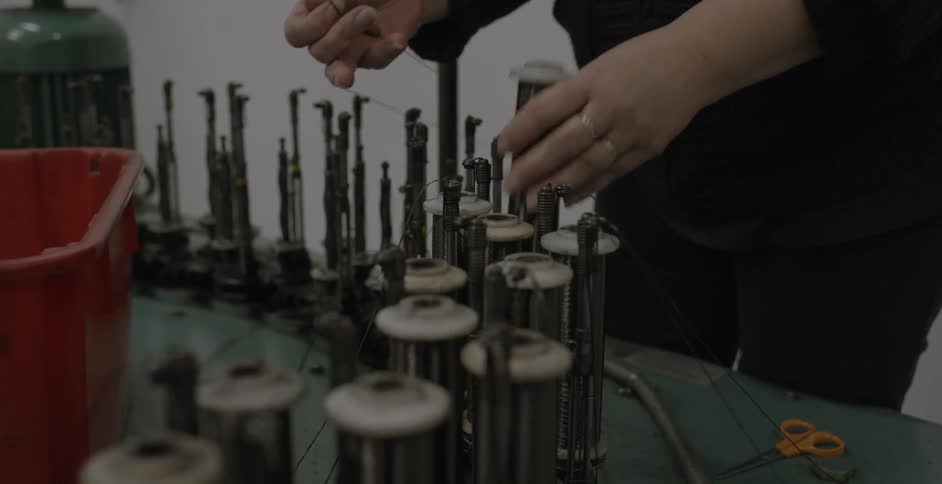 A person is putting spools of thread on a machine