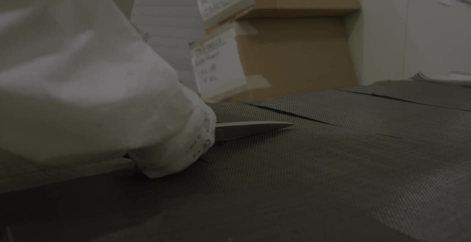 Gloved hands use scissors to cut a black mat
