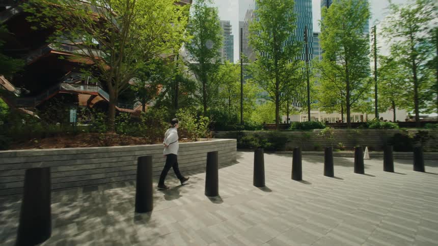 Man with a camera walks past a building with an unusual architecture near downtown
