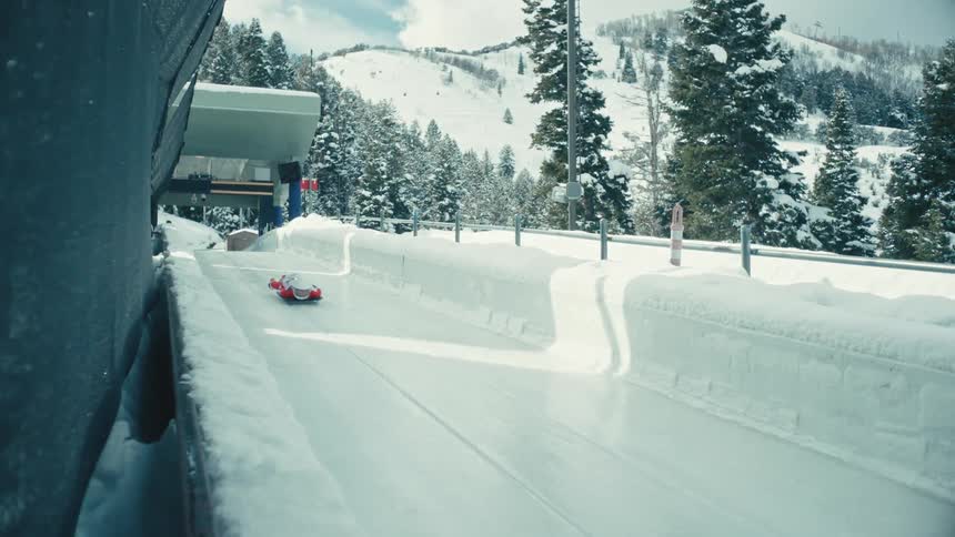 Snow covered bobsled track with a person riding down on a sled