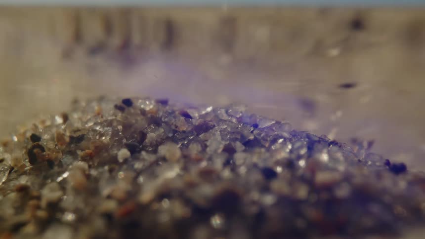 Grains of sand fall in the water