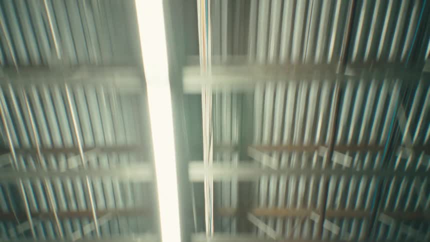 A view of an interior ceiling with several lamps illuminating the room and the roof is made of metal plates