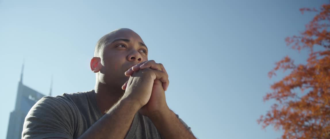 Man sitting with his hands by his face on a sunny day