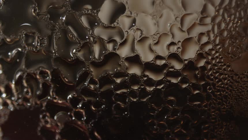 Abstract pattern of water droplets on a dark surface creating a captivating interplay of light and shadow