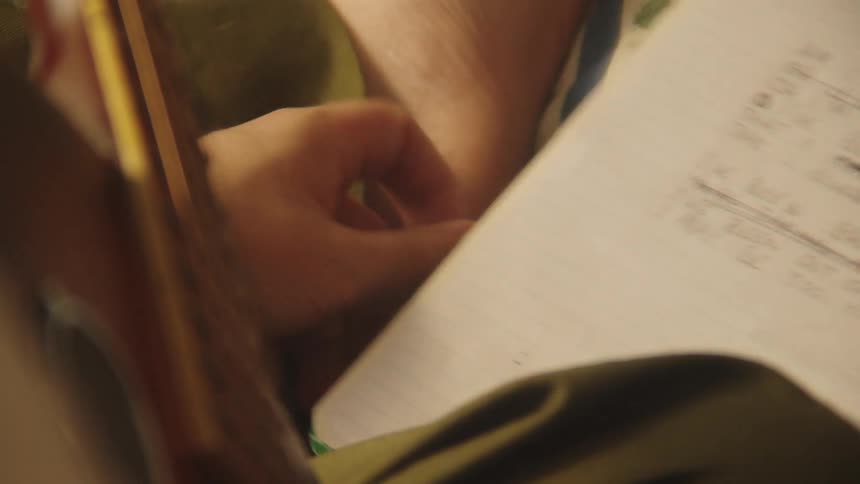 A close up clip of a person writing in a book