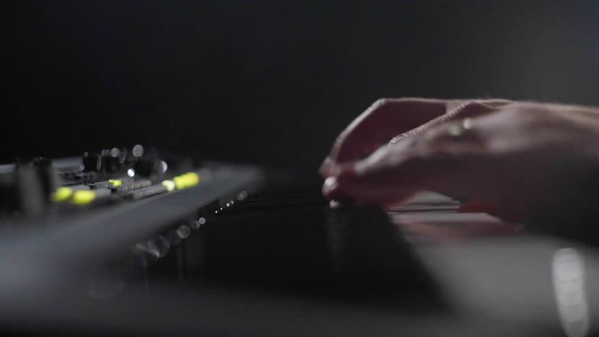 Person playing a piano instrument in a dark lit room