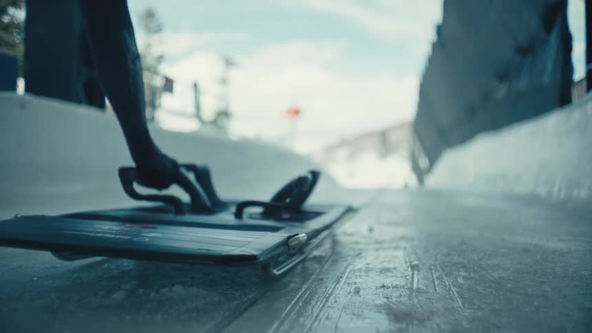 A person is pushing a small platform on an ice rink and he is running