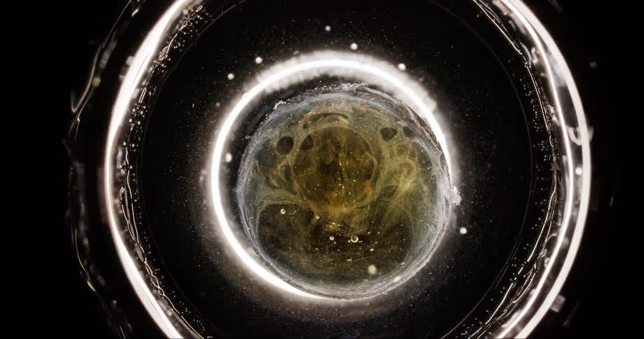 Extreme close up of a round circle with liquid in a shiny surrounding
