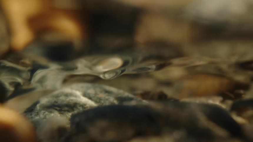 Closeup of underwater river water flowing over small rocks