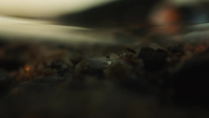 Close up of river water flowing above boulders and minerals