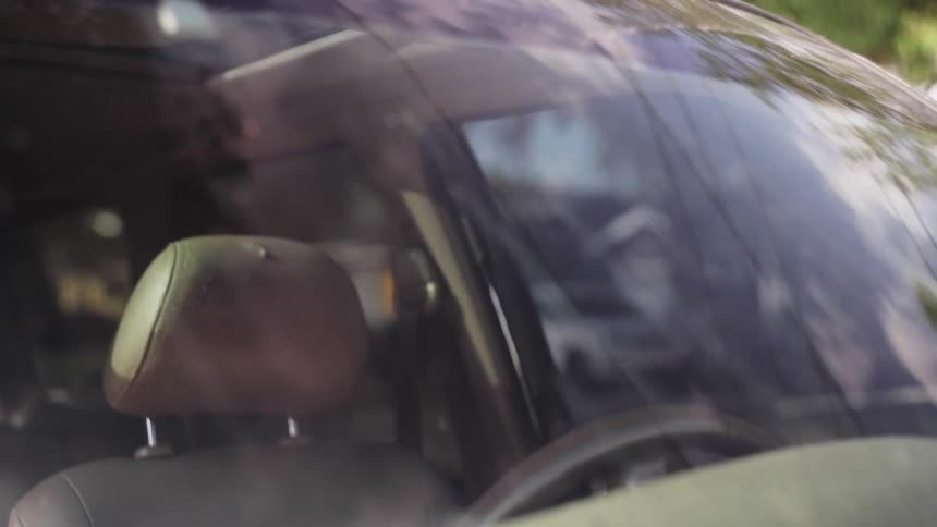 A man exits his parked car and walks away in a city