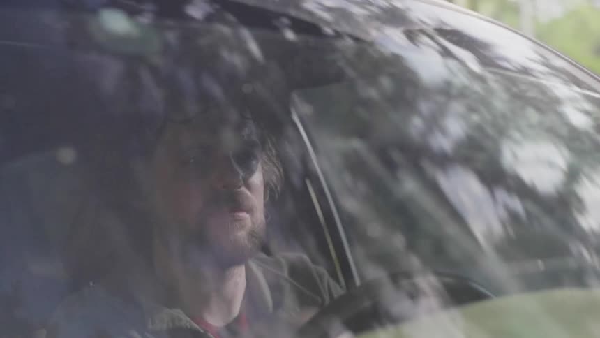 A man is making a turn as he drives a car