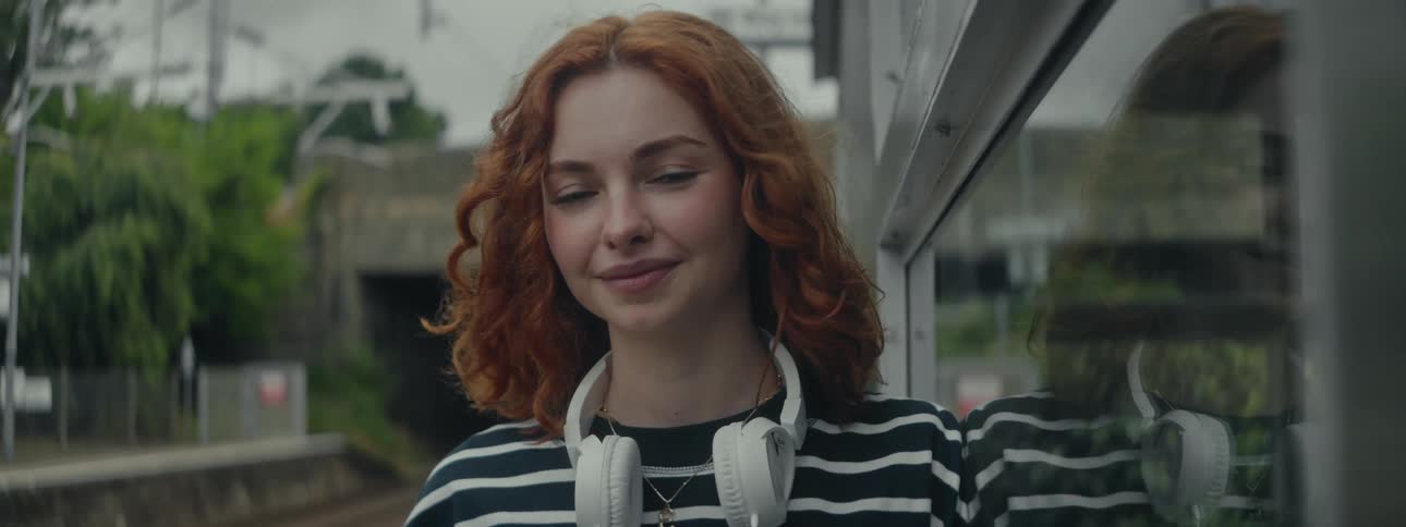Portrait of a curlyhaired redhead with a headset around her neck