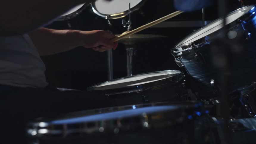 A man is playin the drums in a dark room