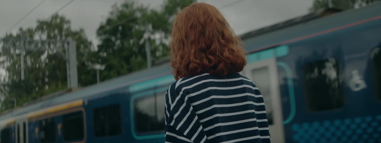Redheaded woman walking next to a train