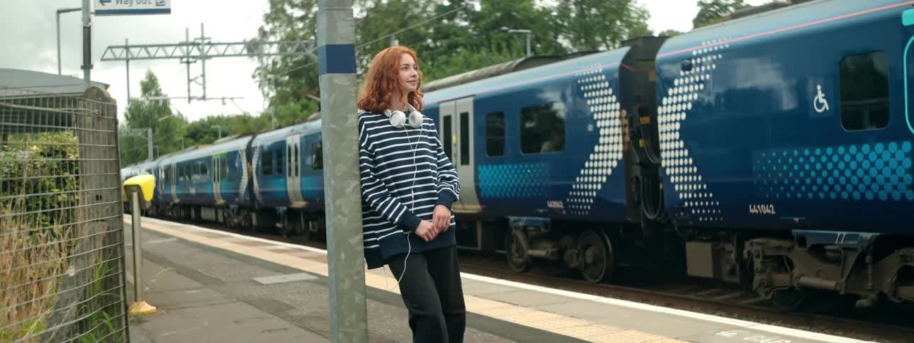 A woman stands near a train