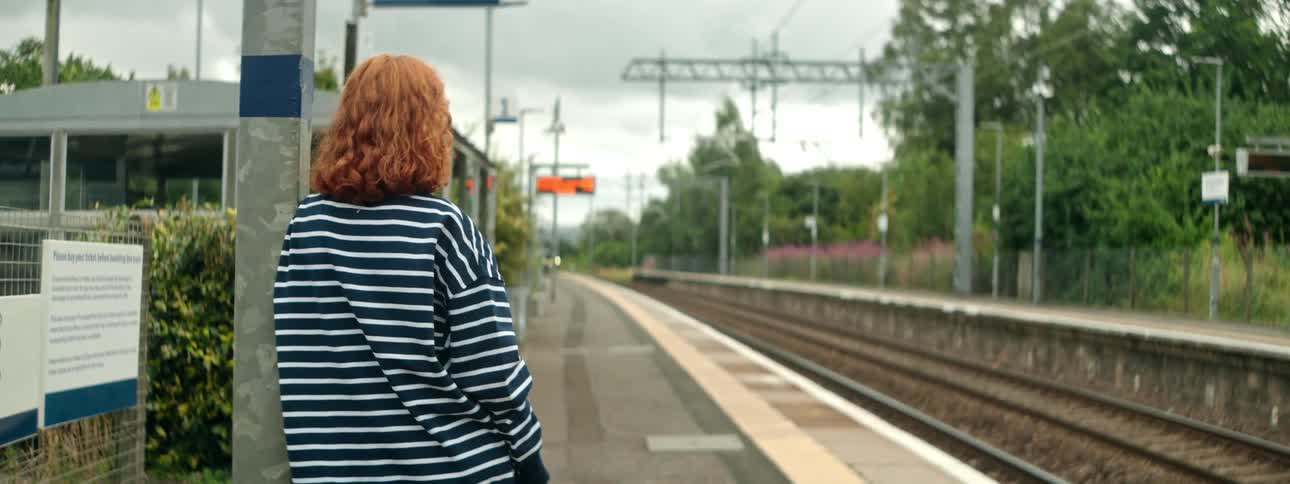 A clip of a lady waiting by the rail side