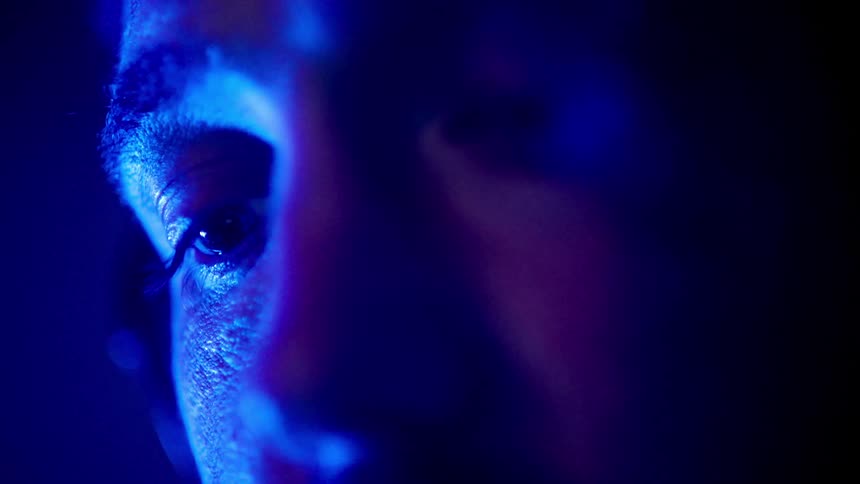 A mans face is shown in an abstract blue color as he cautiously looks up at something