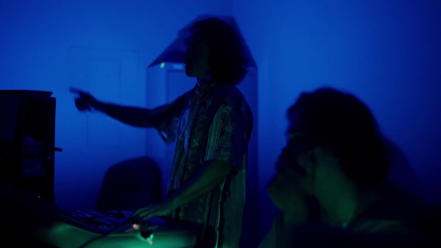 Two men in a dimly lit room with musical instruments