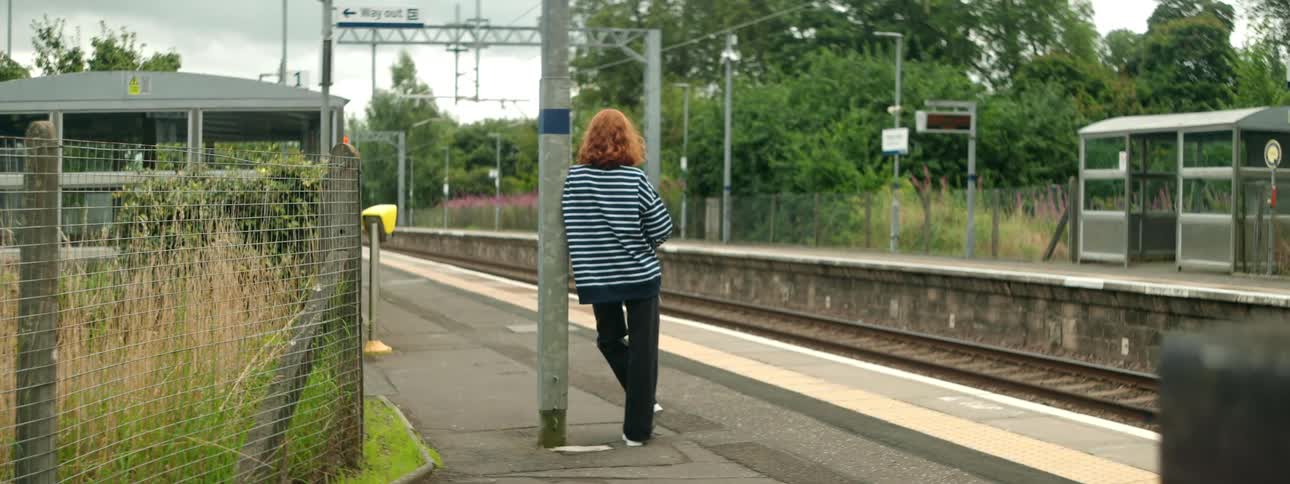A clip of a lady standing by the rail side