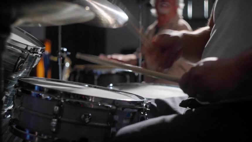 Two men sitting playing drums