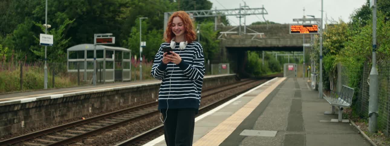 A woman is using her cell phone on the railway platform