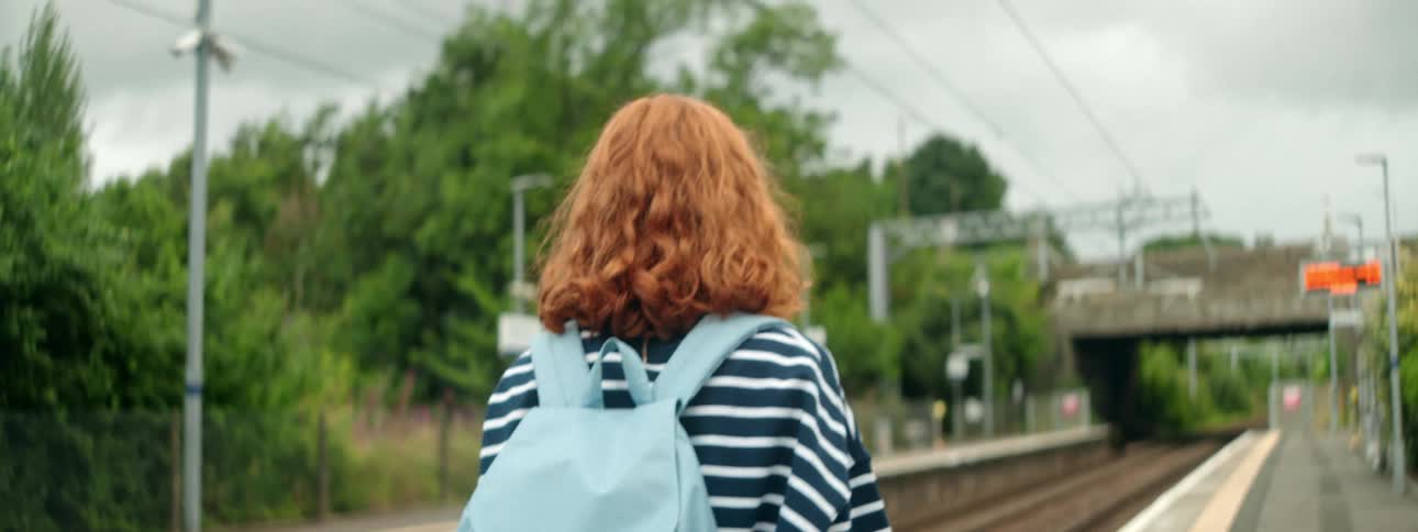 Redhead woman with a backpack walking in a subway station outdoors