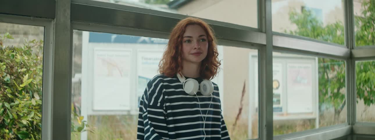 A footage of a lady waiting beside the glass window