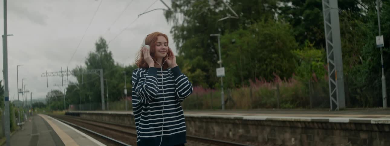 Woman with happy facial expression with white ear leaves next to a subway station