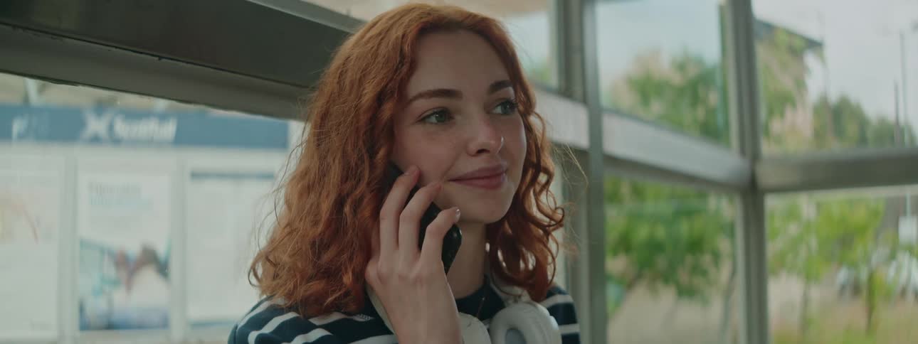 A woman smiles while listening on her phone