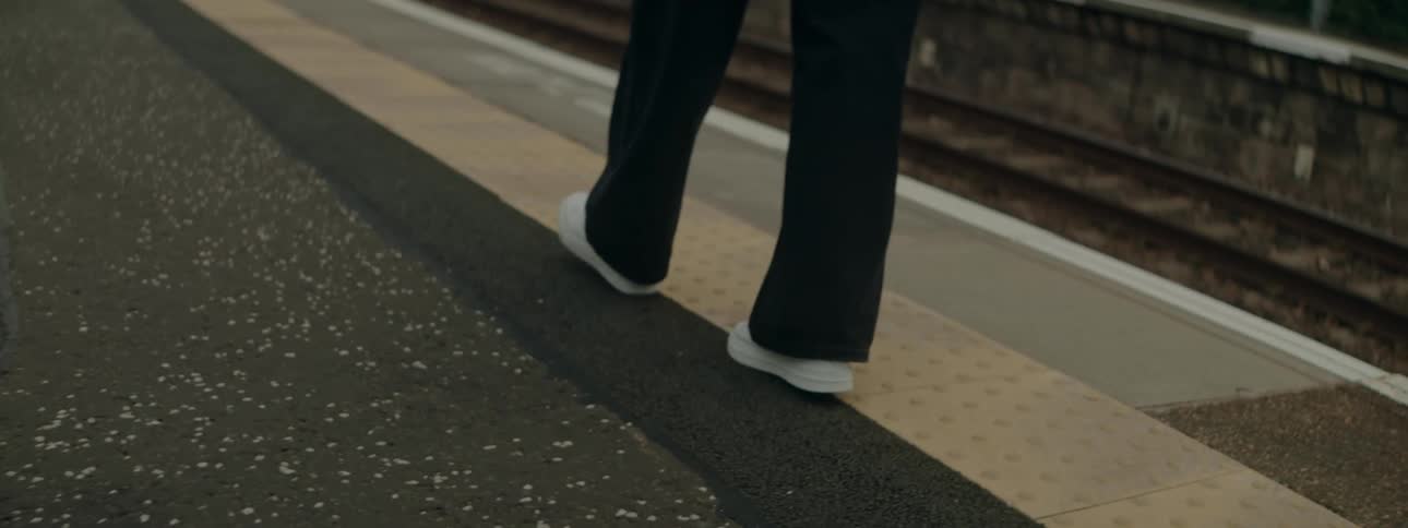 Legs of a person walking next to a train track