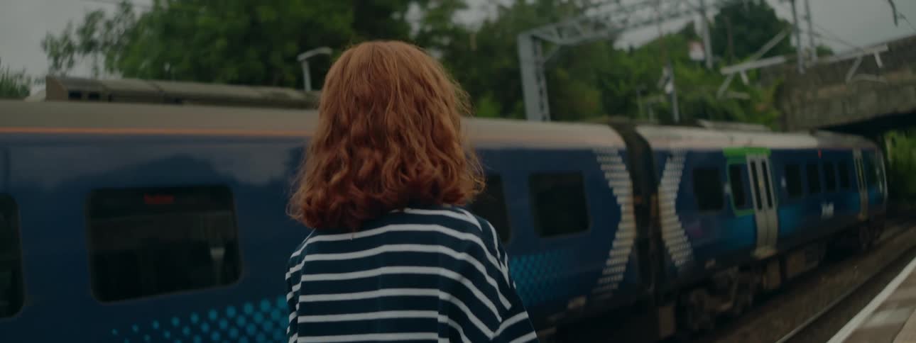 Redhead woman walking next to a blue train