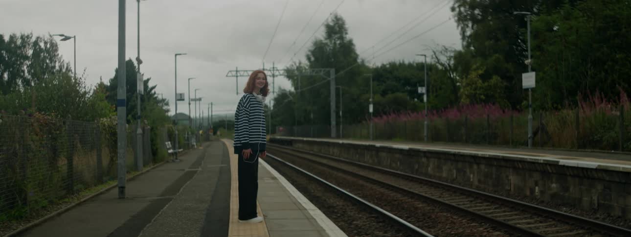 Woman at a station next to a train track waiting