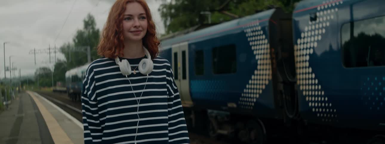 The train stops by a woman on the platform
