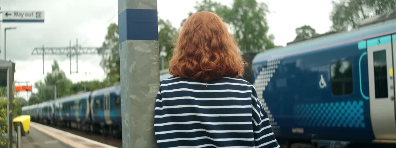 A woman watches a train pull into the station