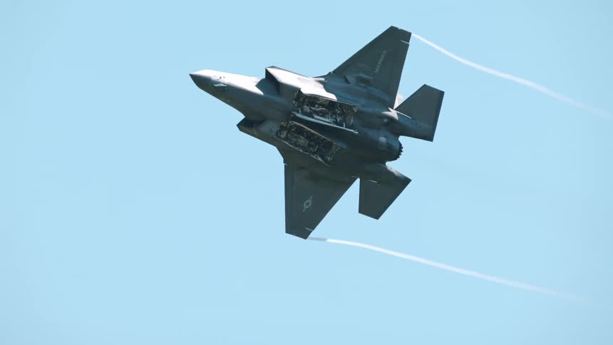 A military aircraft is flying in the air and tipping back and forth