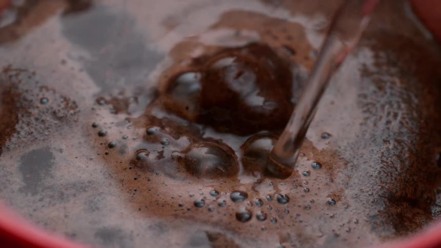 Boiling water is poured into a cup containing coffee