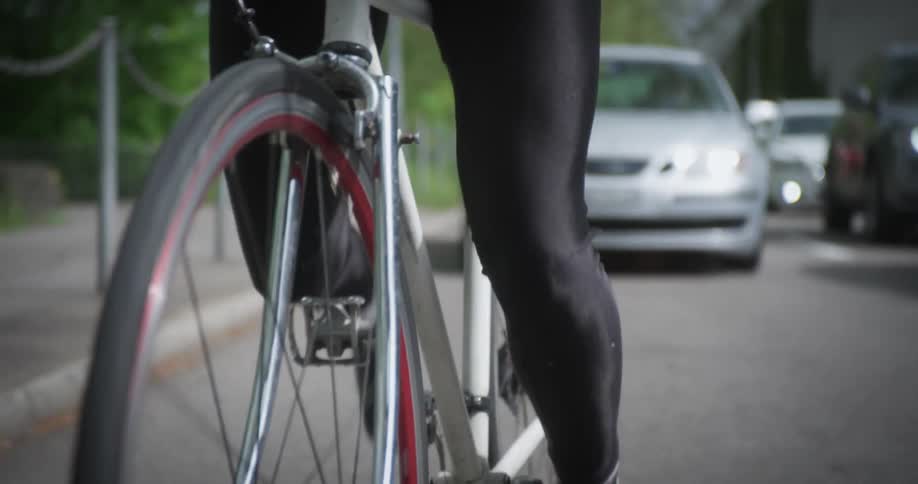 A cyclist rides a bike down a street approaching stopped traffic