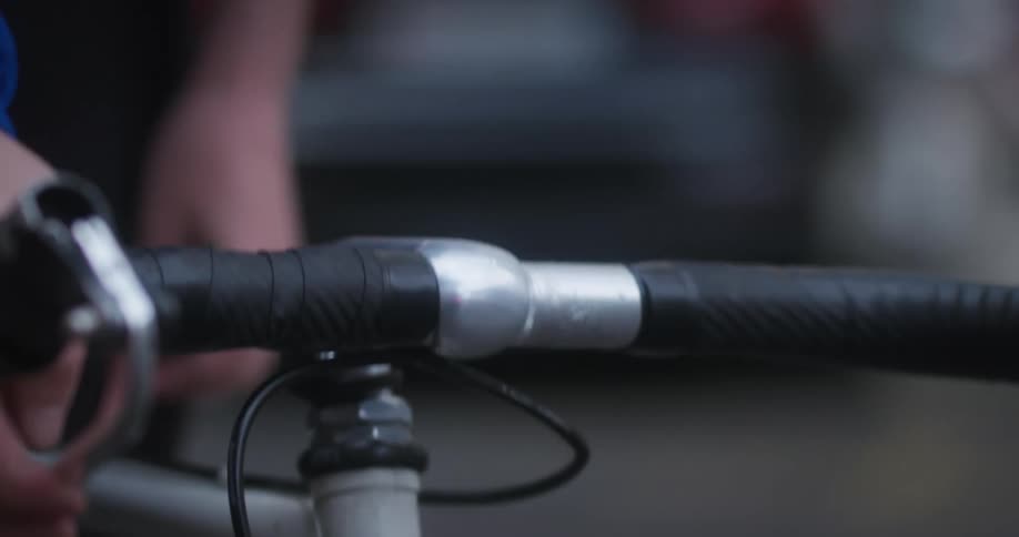 The handlebars of a bicycle are shown with the riders hands on them up close