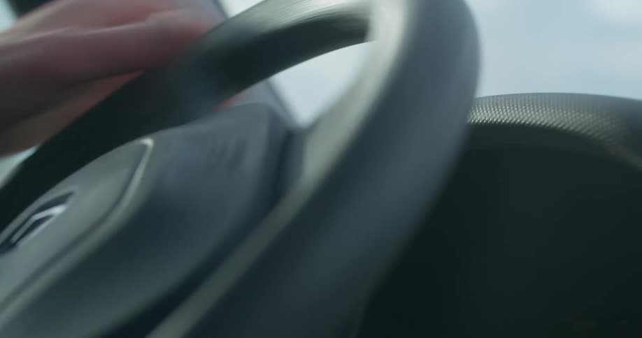 Pair of hands driving and turning the steering wheel to the left