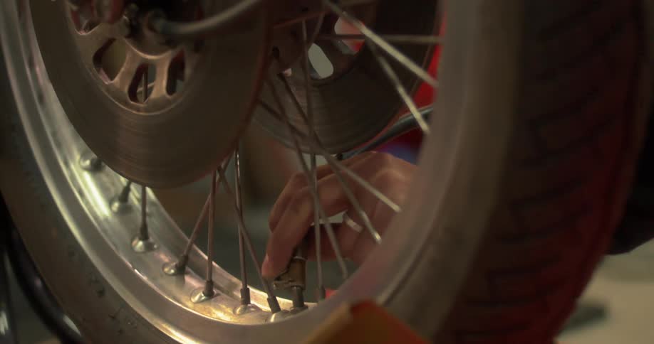 Hand putting an air hose nozzle on a motorcycle wheel