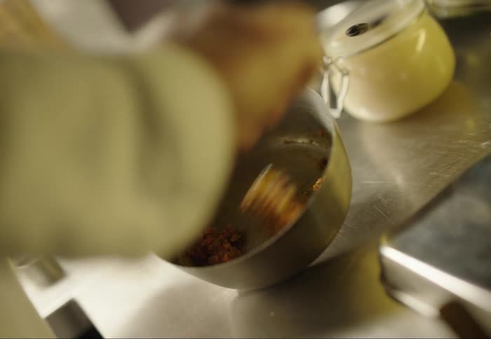A cook is mixing food in a bowl