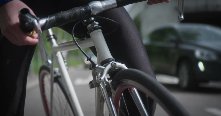 A cyclist stands astride their bike holding onto the handlebars