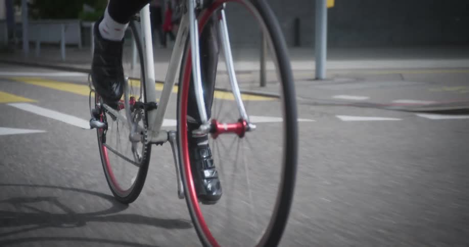Legs of a person cycling on a paved street